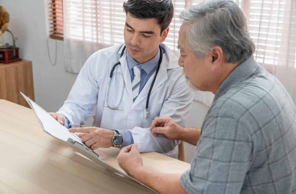 Doctor showing medical chart to older adult during a health consultation at a clinic table