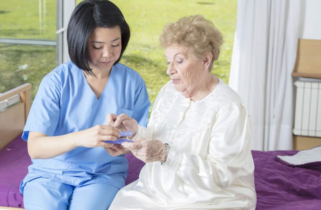 An adult helps their senior parent dress by buttoning a shirt.